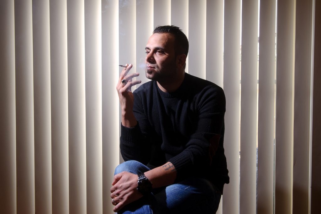 Reza sits at home smoking