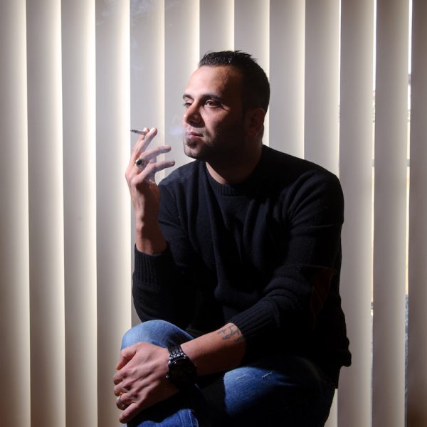 Reza sits at home smoking