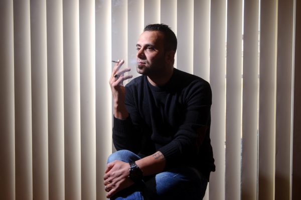 Reza sits at home smoking
